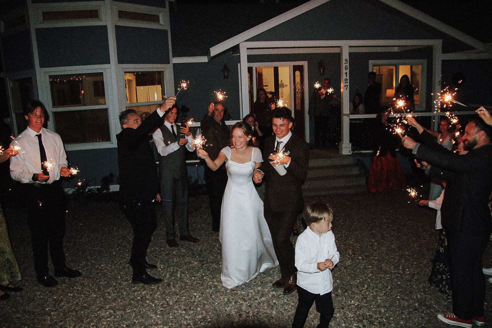 smiling bride and groom holding hands during their nighttime sparkler send-off